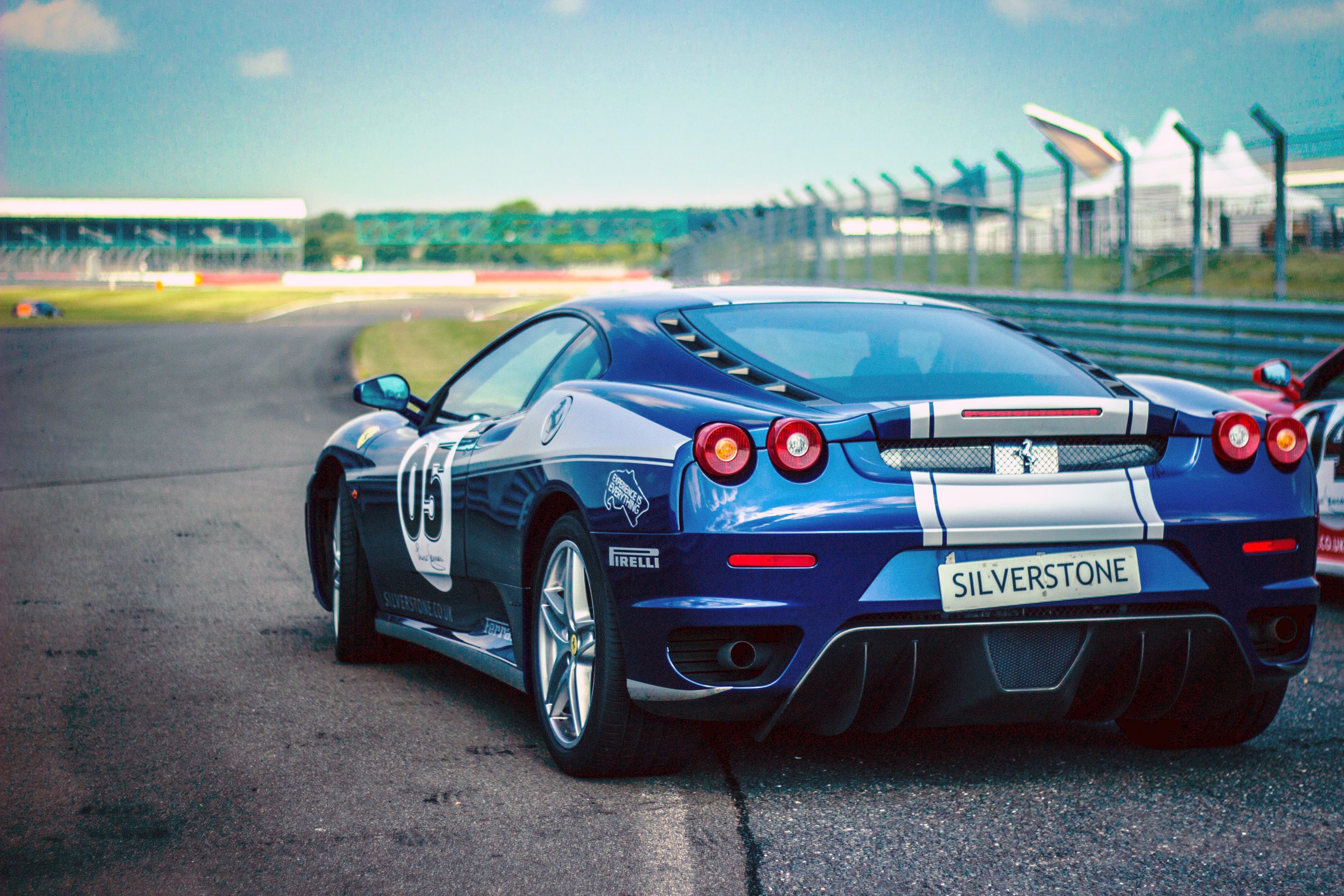 Blue Ferrari F430 with silver stripes seen from behind on the Silverstone circuit