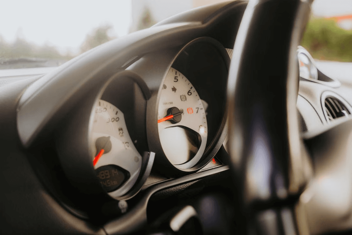 Porsche 911 gauge cluster viewed through the steering wheel, central tachometer and 300 km/h speedometer in focus